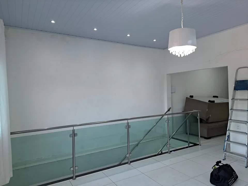 Ambiente interno com forro branco, iluminação embutida e guarda-corpo de vidro