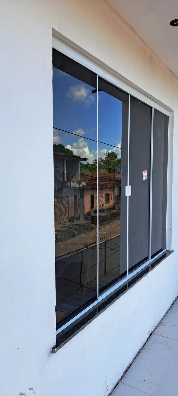 Janela de vidro com esquadria preta instalada em uma fachada clara